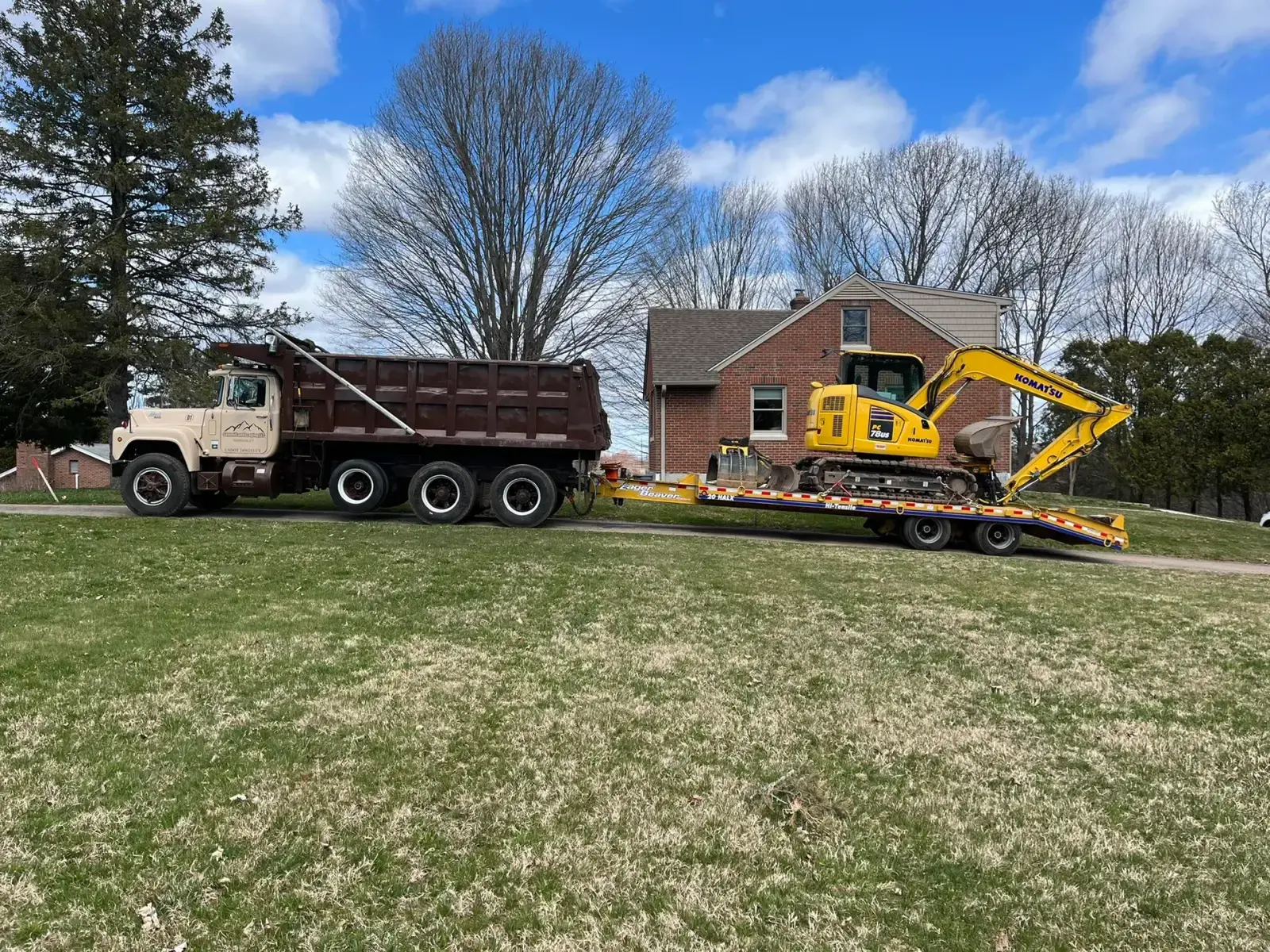 Summit Septic dump truck and a Komatsu mini-excavator loaded on a lowboy trailer at a Connecticut residential job site